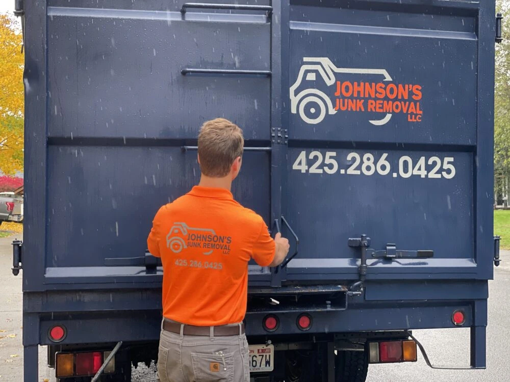 Junk removal professional closing up the truck after loading up home demolition debris