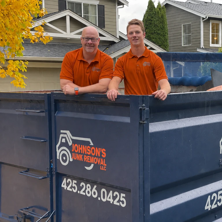 Junk removal professionals posing in the back of the junk removal truck